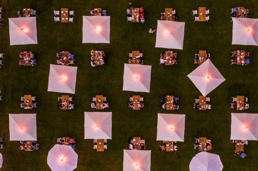Aerial view of an outdoor event with umbrellas and tables